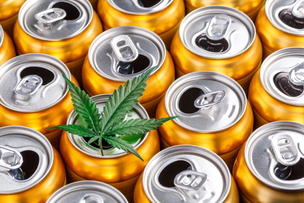 Photo of a cannabis leaf on top of several open beverage cans