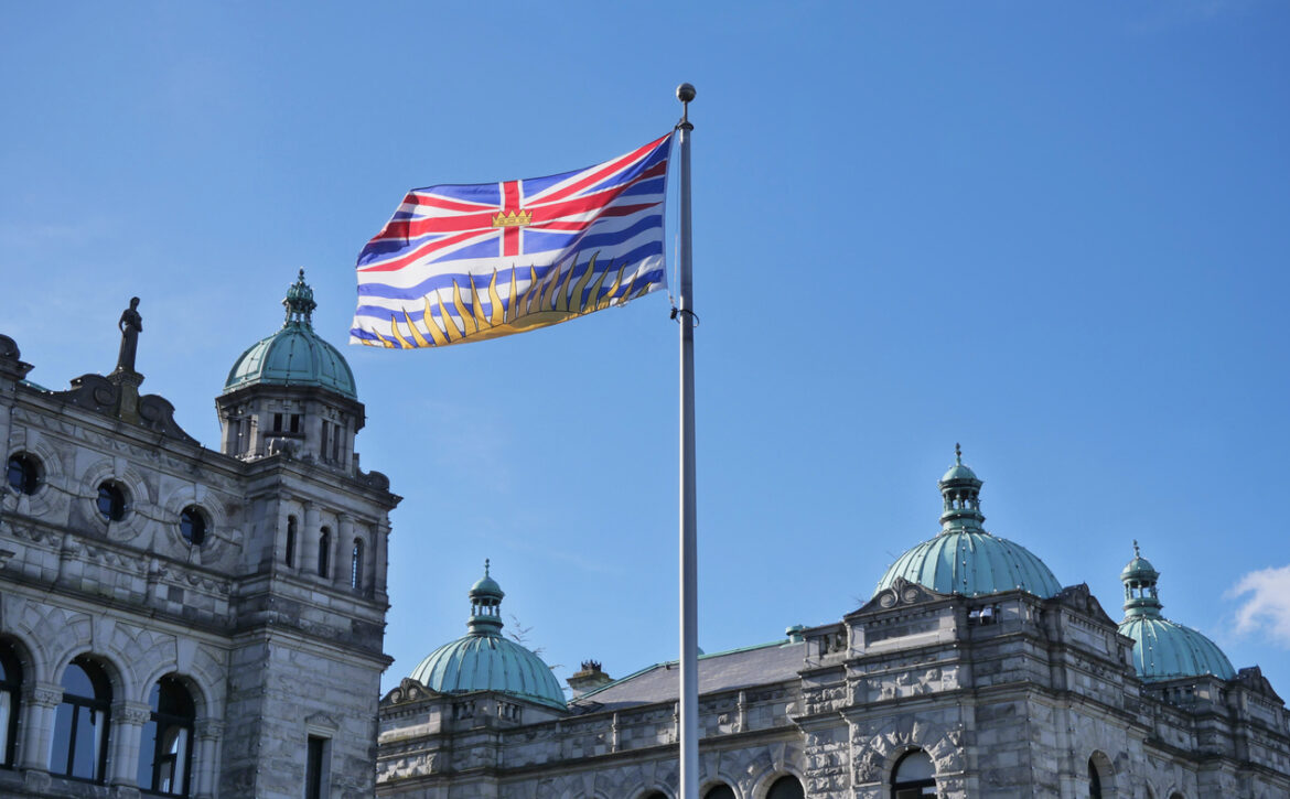 Flag of British Columbia waving in front of the Legislative Assembly of British Columbia