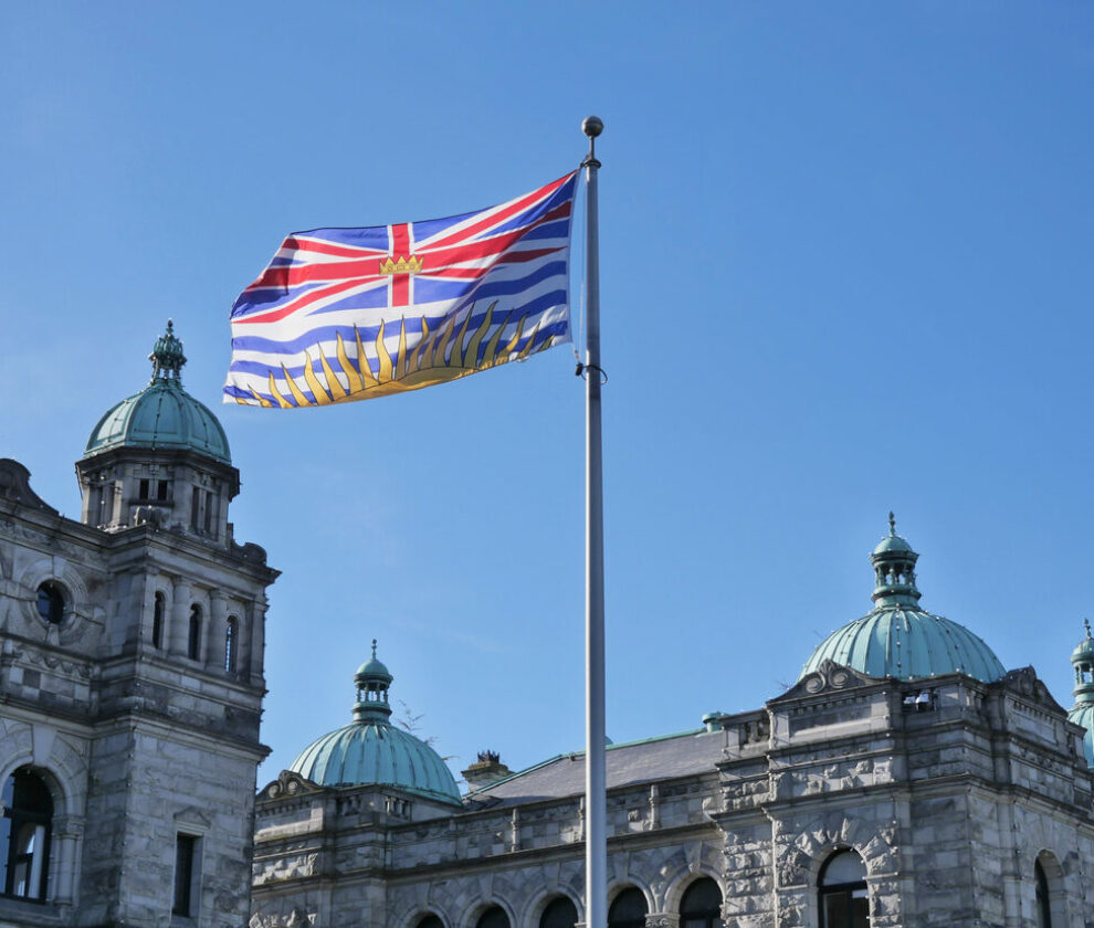 Flag of British Columbia waving in front of the Legislative Assembly of British Columbia